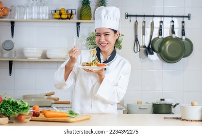 Portrait beautiful Asian professional female chef wearing white uniform, hat, showing plate of spaghetti, cooking in kitchen, making surprising face with happiness. Restaurant, Food Concept - Powered by Shutterstock