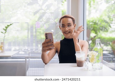 Portrait of beautiful Asian queer LGBT community supporter man with mustache wearing lipstick and jumpsuit using mobile phone in coffee shop - Powered by Shutterstock