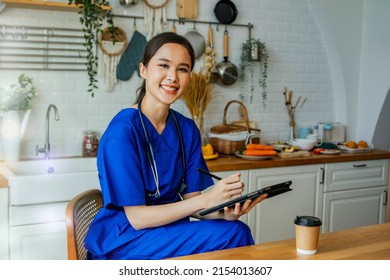 Portrait Beautiful Asian Surgeon Wearing Blue Coat Sits And Takes Notes In The Hospital Kitchen Sit Back And Relax, Take The Time To Check Your Work Schedule On Your Laptop And Smile At The Camera.