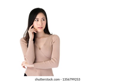 Portrait Of Beautiful Asian Woman In Casual Clothes Looking Serious In A Thinking Gesture With Her Hand Touching Her Face In White Isolated Studio Background With Copy Space