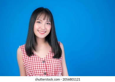 Portrait of Beautiful Asian woman cute girl in red dress with bangs hair style smiling good mood isolated blue background - lifestyle pretty girl Concept