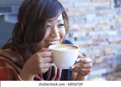 Portrait Of Beautiful Asian Woman Drinking Cappuccino At A Coffee Shop.