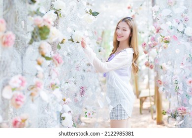 Portrait Beautiful Asian Woman With Good Skin And Long Hair Who Wears A White Shirt And Touches White Flower In The Garden.