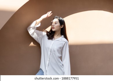 Portrait of a beautiful Asian woman with healthy skin. She uses a sun protection hand that hits her face to protect against UV that has caused her face to dull.
