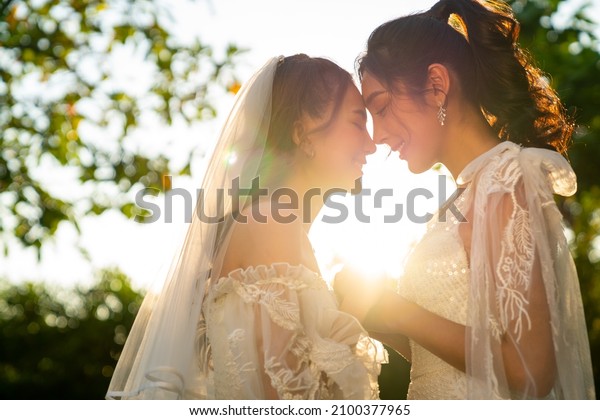Portrait of Beautiful Asian woman lesbian couple\
in wedding dress holding hands walking together in the garden.\
Diversity sexual equality, lgbtq pride, marriage equality and\
Same-sex marriage\
concept