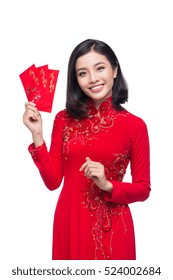 Portrait of a beautiful Asian woman on traditional festival costume Ao Dai holding red pocket - lucky money. Tet holiday. Lunar New Year.