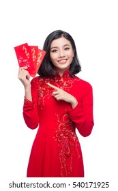 Portrait of a beautiful Asian woman on traditional festival costume Ao Dai holding red pocket - lucky money. Tet holiday. Lunar New Year.
