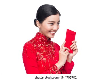 Portrait of a beautiful Asian woman on traditional festival costume Ao Dai holding red pocket - lucky money. Tet holiday. Lunar New Year.