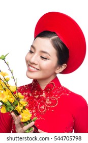 Portrait of a beautiful Asian woman on traditional festival costume Ao Dai holding Hoa Mai tree (Ochna Integerrima) flower. Tet holiday. Lunar New Year.