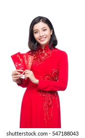 Portrait of a beautiful Asian woman on traditional festival costume Ao Dai holding red pocket - lucky money. Tet holiday. Lunar New Year.