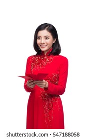 Portrait of a beautiful Asian woman on traditional festival costume Ao Dai holding red pocket - lucky money. Tet holiday. Lunar New Year.