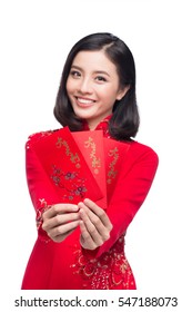 Portrait of a beautiful Asian woman on traditional festival costume Ao Dai holding red pocket - lucky money. Tet holiday. Lunar New Year.