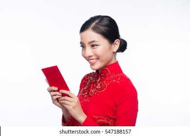 Portrait of a beautiful Asian woman on traditional festival costume Ao Dai holding red pocket - lucky money. Tet holiday. Lunar New Year.