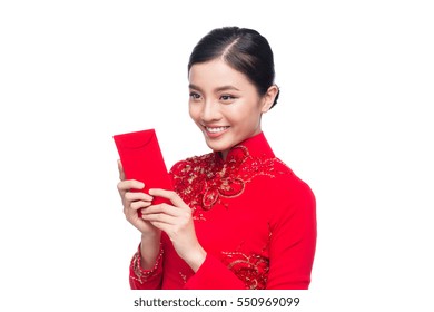 Portrait of a beautiful Asian woman on traditional festival costume Ao Dai holding red pocket - lucky money. Tet holiday. Lunar New Year.