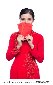 Portrait of a beautiful Asian woman on traditional festival costume Ao Dai holding red pocket - lucky money. Tet holiday. Lunar New Year.