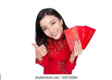 Portrait of a beautiful Asian woman on traditional festival costume Ao Dai holding red pocket - lucky money. Tet holiday. Lunar New Year.