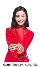 Portrait of a beautiful Asian woman on traditional festival costume Ao Dai holding red pocket - lucky money. Tet holiday. Lunar New Year.