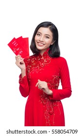 Portrait of a beautiful Asian woman on traditional festival costume Ao Dai holding red pocket - lucky money. Tet holiday. Lunar New Year.