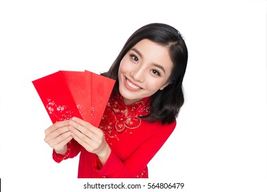 Portrait of a beautiful Asian woman on traditional festival costume Ao Dai holding red pocket - lucky money. Tet holiday. Lunar New Year.