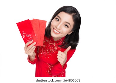 Portrait of a beautiful Asian woman on traditional festival costume Ao Dai holding red pocket - lucky money. Tet holiday. Lunar New Year.