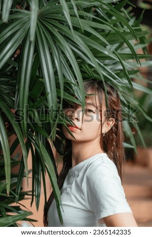 Portrait of beautiful asian woman smiling and enjoying the nature on background of green leaves, tropical wild aesthetic exotic concept, Zen, love forest