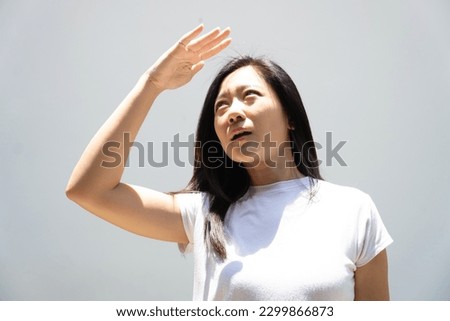 Portrait of a beautiful Asian woman using her hands to block the sun from the sun. skin care or beauty concept