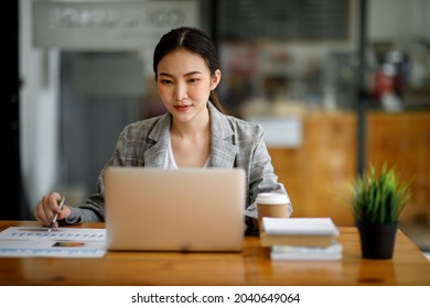 Portrait Of Beautiful Asian Young Business Woman Working Audit And Calculating Expense Annual Financial Report Balance Sheet Statement,doing Finance Making Notes On Paper Graph Data Checking Document.