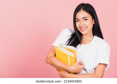 Portrait of beautiful Asian young woman teenage smiling hugging books, female person holding book multicolor, studio shot isolated on pink background with copy space, education concept