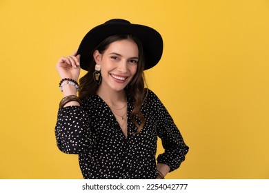 portrait of beautiful attractive woman posing isolated on yellow background wearing black dotted dress and black hat stylish boho trend, spring summer fashion style accessories, smiling happy mood