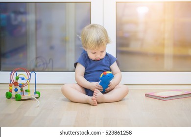 Portrait Of A Beautiful Baby Boy On The Floor With Music Phone Toys. 1,5 Year-old Child Playing With Educational Cup Toys At Home. Little Blond Kid With Blue Eyes Is Playing With Toy At Home Indoors