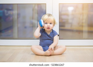 Portrait Of A Beautiful Baby Boy On The Floor With Music Phone Toys. 1,5 Year-old Child Playing With Educational Cup Toys At Home. Little Blond Kid With Blue Eyes Is Playing With Toy At Home Indoors