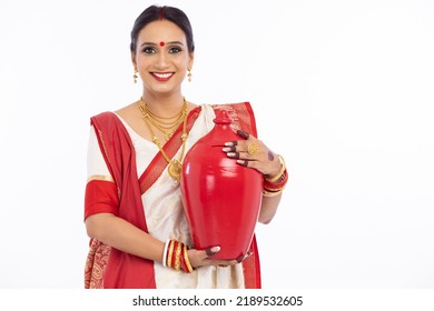 Portrait Of Beautiful Bengali Woman Holding Earthen Piggy Bank In Traditional Red And White Sari 
