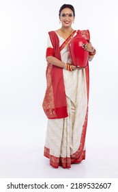 Portrait Of Beautiful Bengali Woman Holding Earthen Piggy Bank In Traditional Red And White Sari 
