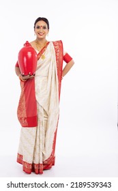 Portrait Of Beautiful Bengali Woman Holding Earthen Piggy Bank In Traditional Red And White Sari 
