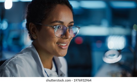 Portrait Of Beautiful Black Latin Woman Computer Screen Reflecting In Her Glasses. Young Intelligent Female Scientist Working In Laboratory. Background Bokeh Blue With High-Tech Technological Lights
