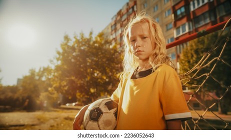 Portrait of a Beautiful Blond Girl in Yellow T-Shirt Holding a Soccer Ball, Standing Next to a Goal Gate in a Backyard. Young Football Player Looking at Camera, Being Focused. Cold Color Grading. - Shutterstock ID 2236052643