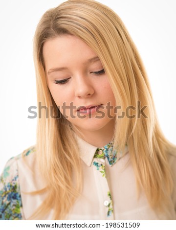 Portrait of a beautiful blond teenage girl looking down isolated against a white background.