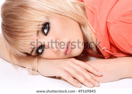 Portrait of beautiful blond thoughtful teen girl with trendy make-up lying on white background