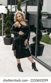 The Portrait Of Beautiful Blond Woman In Black Leather Jacket And Long Dress. Short Hair, Makeup, Style. Everyday Fashion Look. Modern Background.