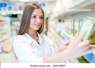 Portrait Of Beautiful Blonde Female Pharmacist Reading A Label In Drug Store