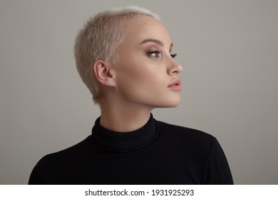 Portrait Of A Beautiful Blonde Woman With A Short Hair On A Gray Background.