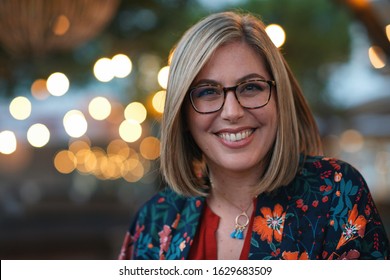 Portrait beautiful blonde woman smiling happy in city evening with lights in background
