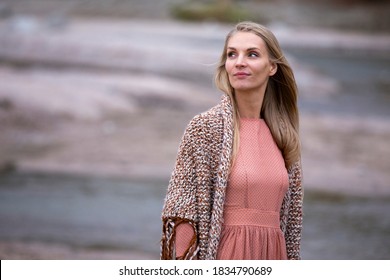 Portrait of a  beautiful blonde young woman wearing knitted shawl in a fall landscape
