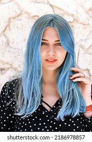 Portrait beautiful blue  eyed woman and blue hair looking into the camera against light marble wall  Hair dyeing  coloring  Hair care  hairdressing  trichology