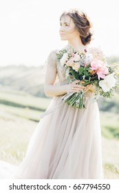 Portrait of a beautiful bride with a bouquet in the nature. fine art photography.