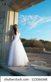 Portrait of beautiful bride in white dress near the old wall.