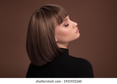 Portrait einer schönen braunhaarigen Frau mit einem kurzen Haarschnitt auf braunem Hintergrund