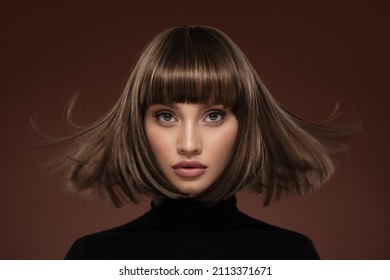 Portrait of a beautiful brown-haired woman with a short haircut on a brown background