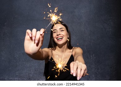 Portrait of a beautiful brunette in a black dress with sparklers. - Powered by Shutterstock