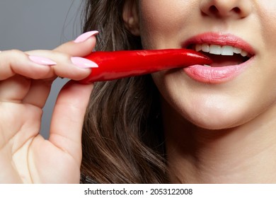 Portrait Of Beautiful Brunette Female Biting Spicy Hot Red Cayenne Chilli Pepper